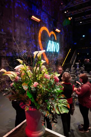 AWO Neujahrsempfang 2023: Ein Blumengesteck vor dem an die Wand projizierten AWO-Logo in der Kulturbrauerei