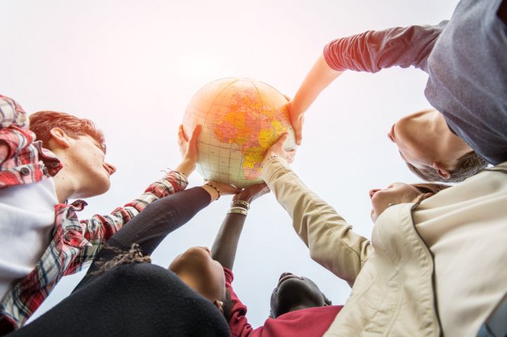Junge Menschen halten einen Globus hoch