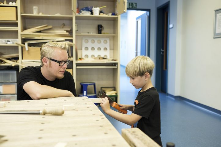 Mann und Kind in einem Werkraum am handwerken