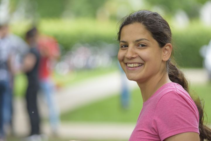 Eine Frau im rosa Shirt lacht in die Kamera