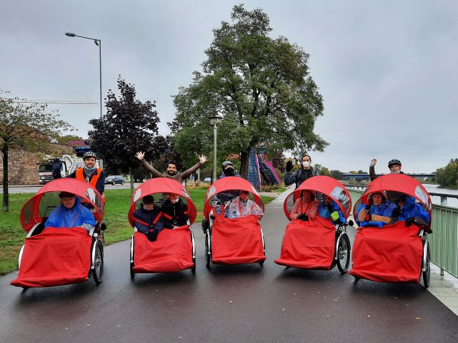 Menschen in Rikshas werden von anderen Menschen im regen geschoben